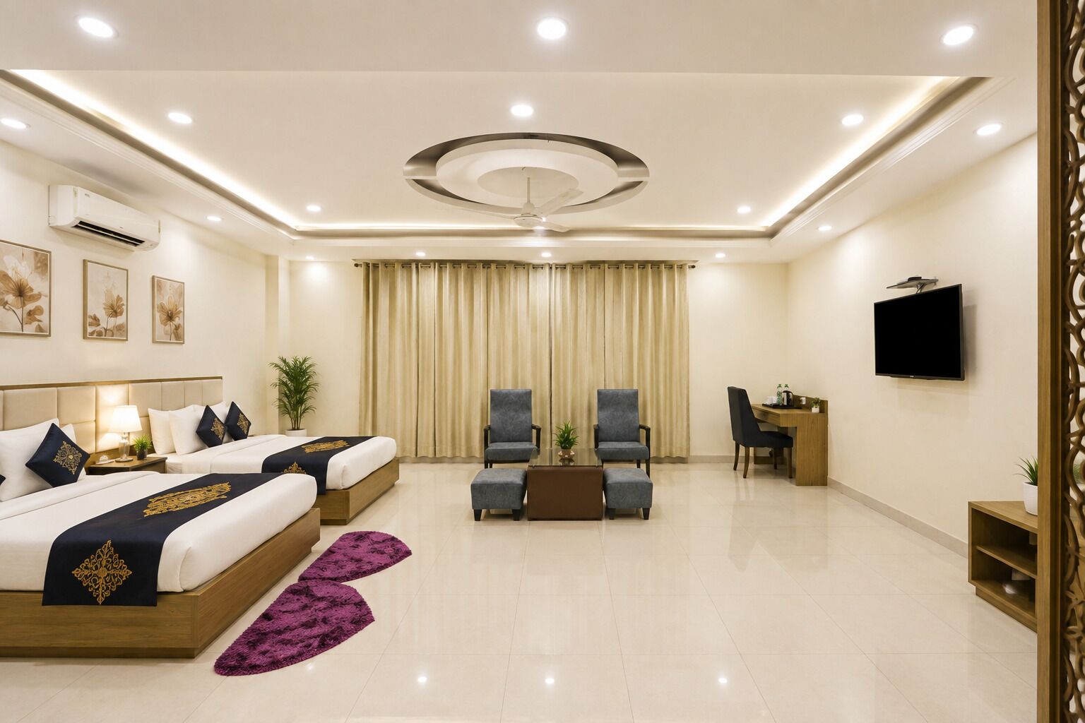 Une chambre d’hôtel comprenant un lit, deux fauteuils, un bureau et un téléviseur.