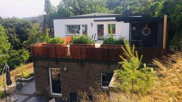Una casa moderna con techo plano, ventanas grandes y terraza de madera.