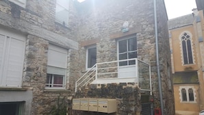 Un edificio in pietra con un piccolo balcone, una cassetta delle lettere e una finestra con persiane.