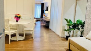 A modern hotel room with a wooden floor, a white dining area with a table and chairs, a sofa, and a large mirror. - Prestige Rooms Chiaia (Naples)