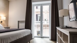 A hotel room with a bed, a nightstand, a lamp, a dresser, and a sliding glass door to the balcony. - Prestige Rooms Chiaia (Naples)