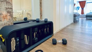 A gym area with a weight bench, dumbbells, and a resistance band. - Prestige Rooms Chiaia (Naples)