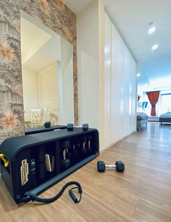 A gym area with a weight bench, dumbbells, and a resistance band. - Prestige Rooms Chiaia (Naples)