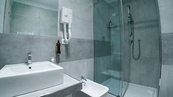 A modern bathroom with a glass-enclosed shower, a sink, and a bidet.