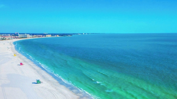A beach with clear turquoise water, a sandy shore, and a few beach umbrellas. - Tiny House Siesta- perfect tiny house for two! (Sarasota)