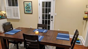 A dining room with a wooden table, four chairs, and blue placemats. - Master's Rental - House, Walking distance to Smokehouse BBQ and a coffee shop (Augusta)