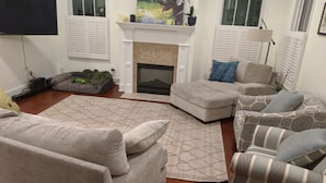 A living room with a fireplace, a sofa, a chair, and a patterned rug. - Master's Rental - House, Walking distance to Smokehouse BBQ and a coffee shop (Augusta)