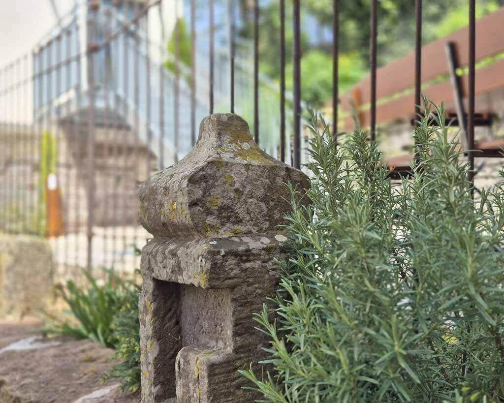 Una estructura de piedra con la parte superior erosionada, rodeada de vegetación.