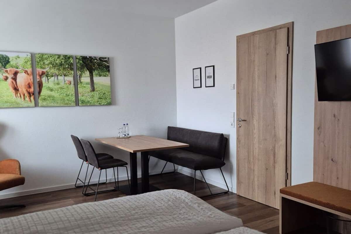 A bedroom with two beds, a desk with a chair, a TV, and a wardrobe.