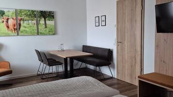 A bedroom with two beds, a desk with a chair, a TV, and a wardrobe.