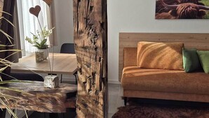 A room with a wooden dining table, a sofa with cushions, a painting of a bull, and a rustic wooden pillar.