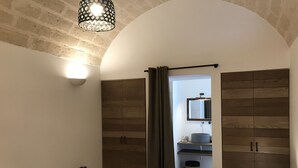 Un dormitorio con una cama grande, un armario de madera y un baño visible a través de una puerta abierta.