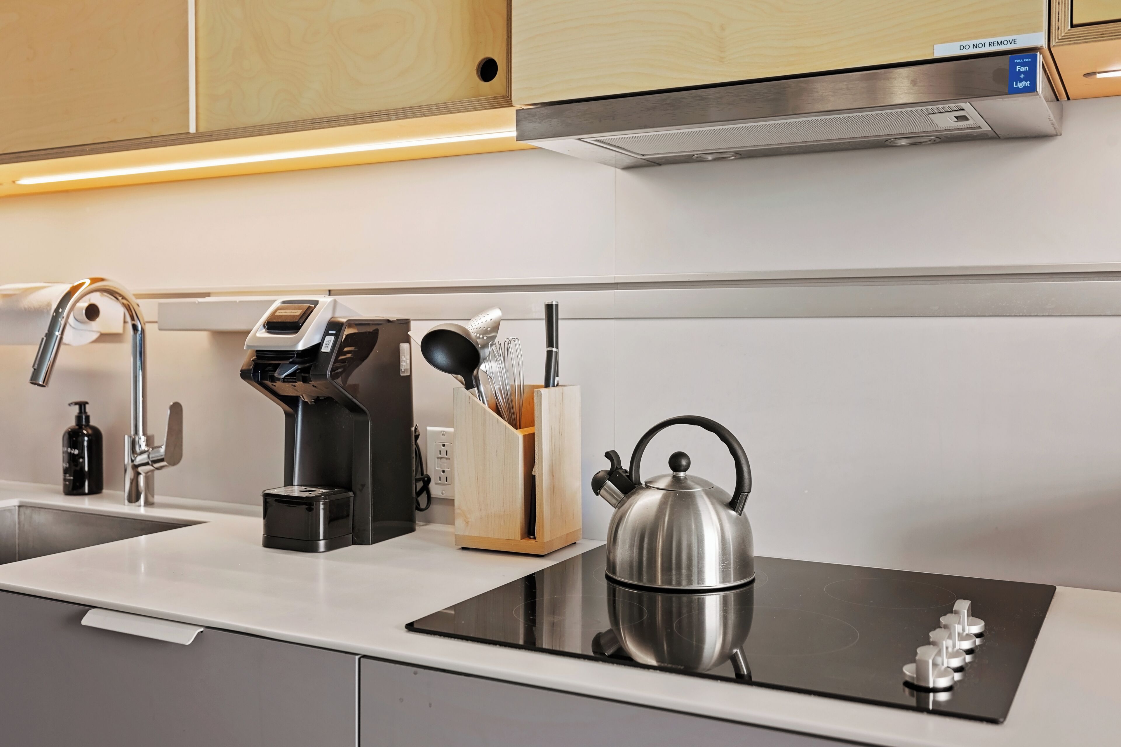 A modern kitchen with a built-in stove, a kettle, a coffee machine, and a knife block.