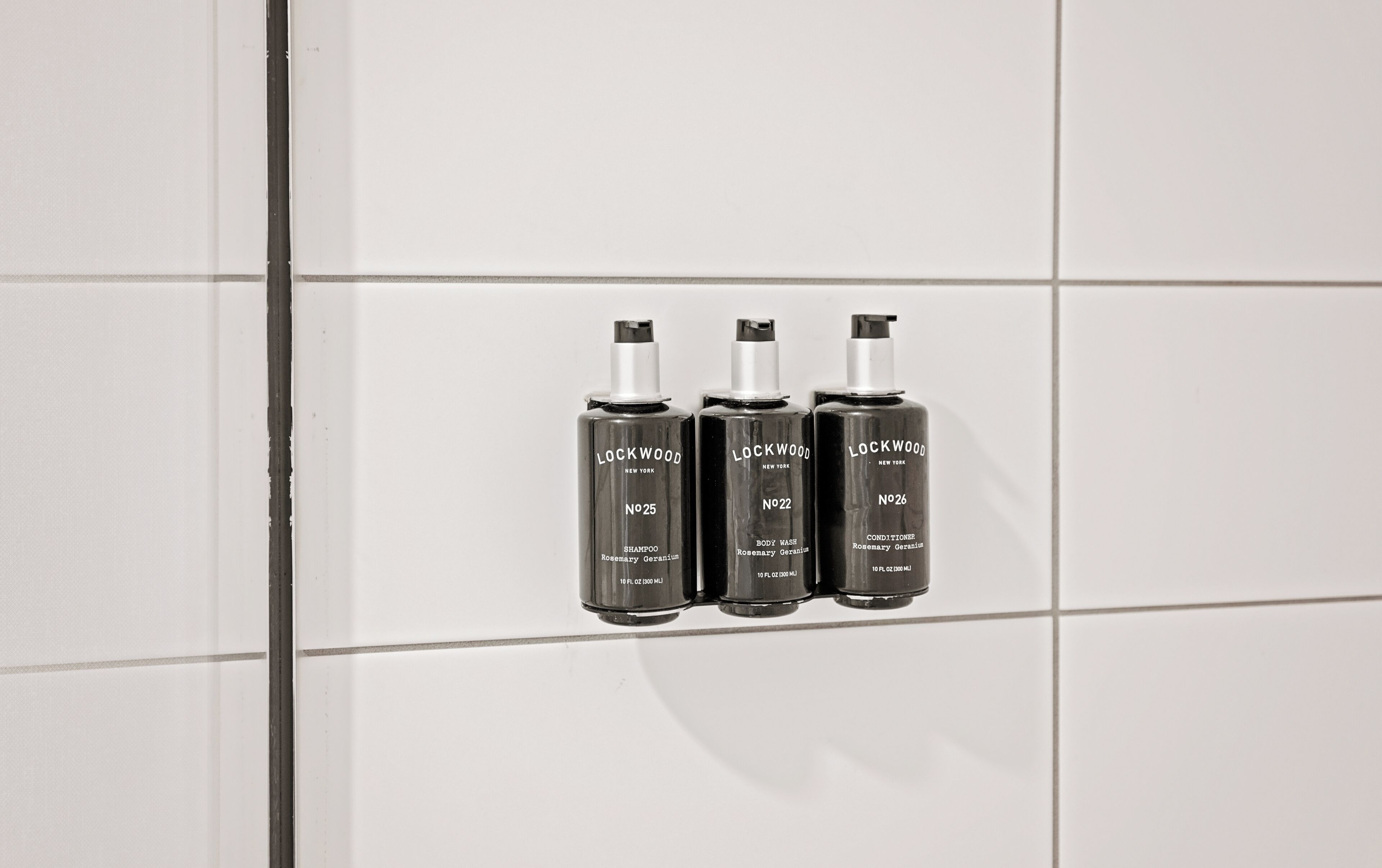 Drei Lockwood New York Shampoo-Flaschen an einer gefliesten Wand.