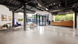 A modern office space with a reception desk, seating area, and a green wall. - Harthall Hotel (Nashville)