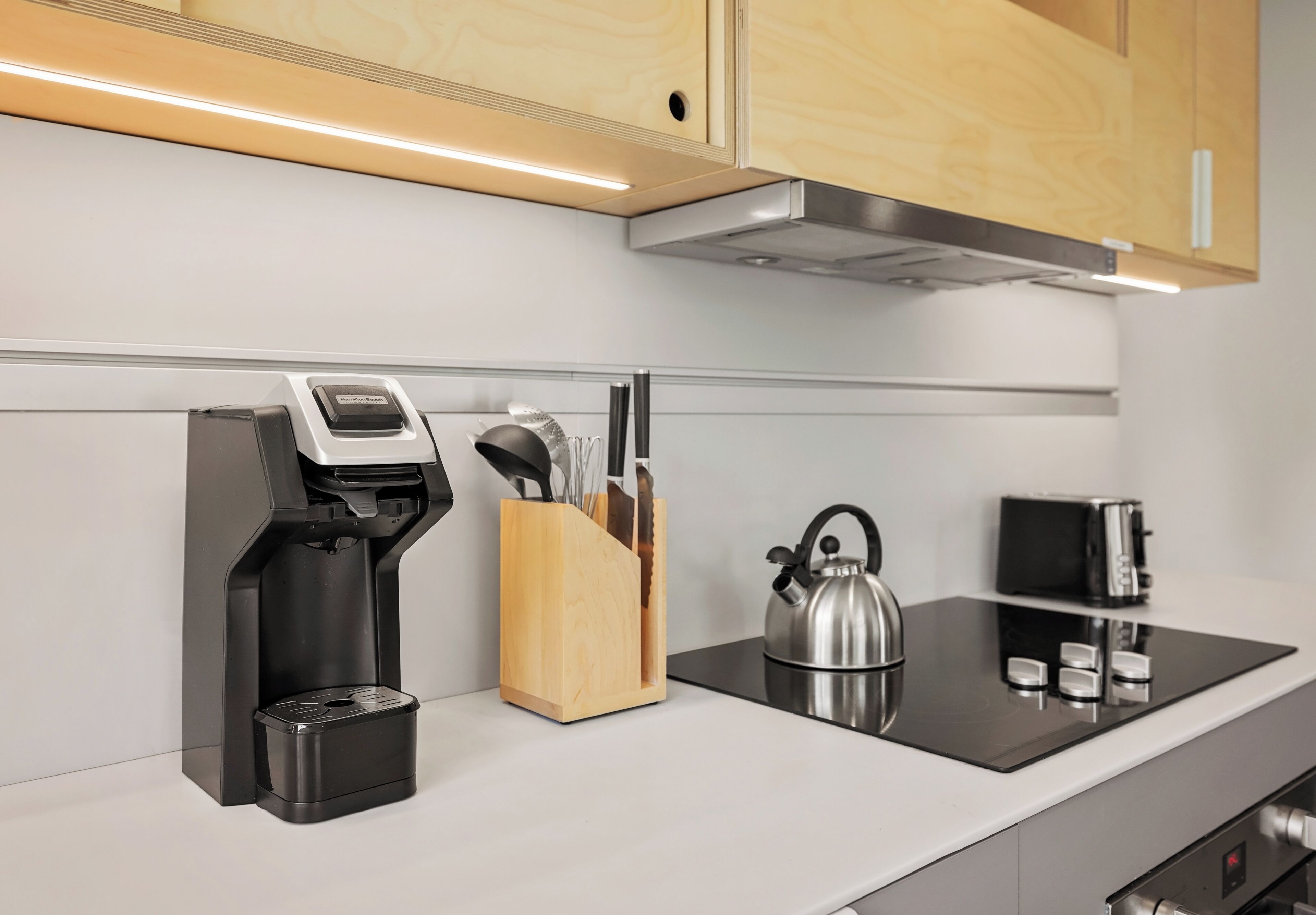A modern kitchen with a coffee machine, a kettle, a toaster, and a knife block.