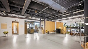 A spacious interior with exposed ductwork, a wooden reception desk, and a seating area. - Harthall Hotel (Nashville)