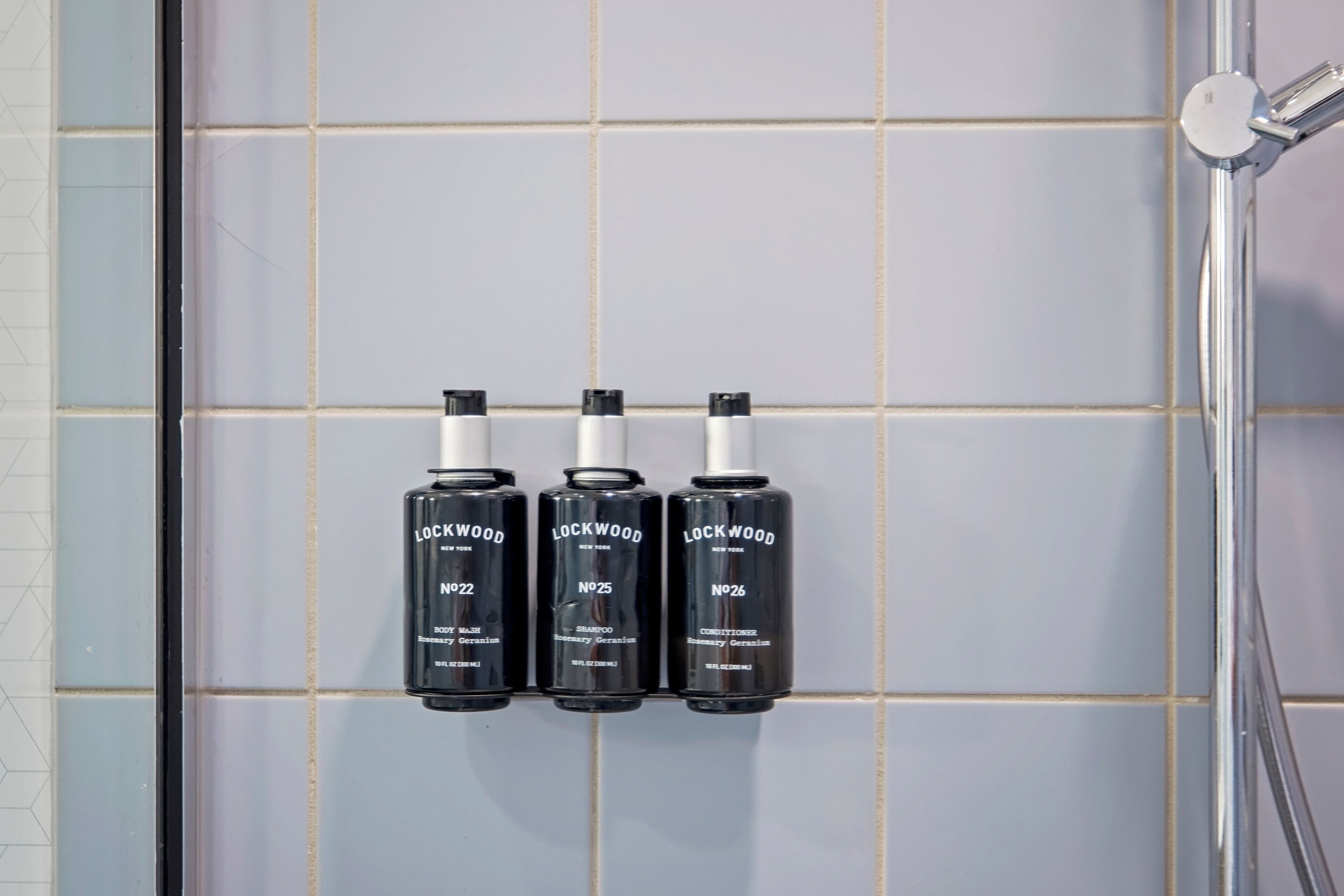 Three Lockwood hair care products on a tiled wall.