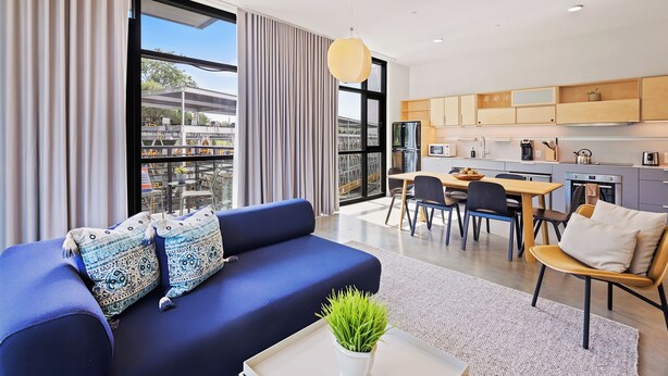A modern living room with a sofa, a dining area, and a kitchen with wooden cabinets. - Harthall Hotel (Nashville)
