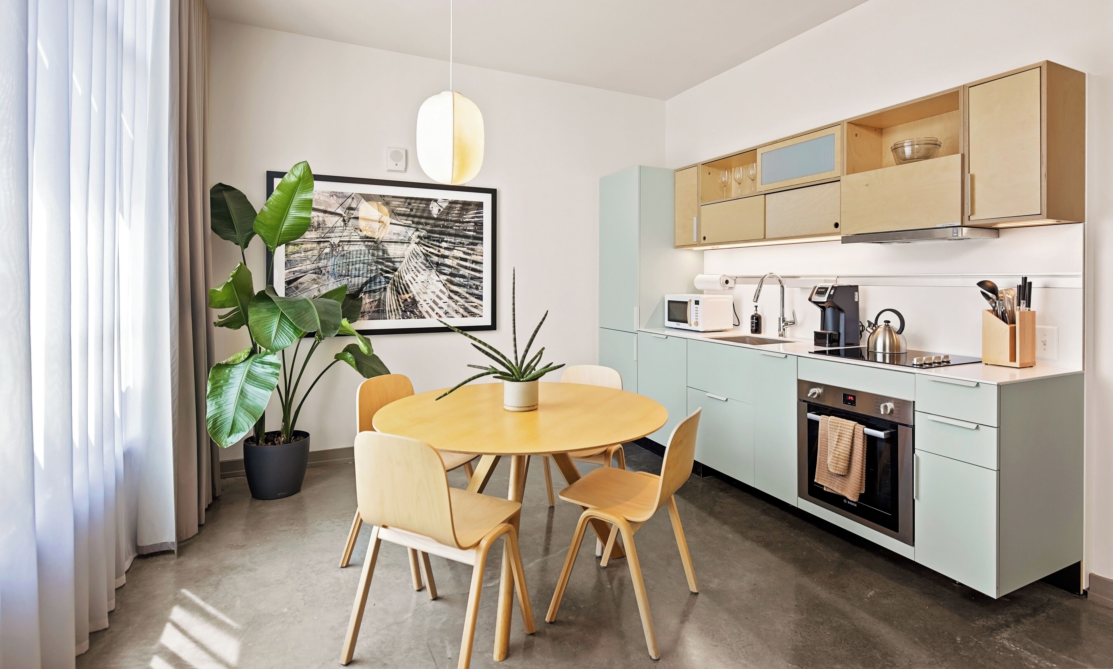 A modern kitchen with light blue cabinets, a round wooden table, and chairs.