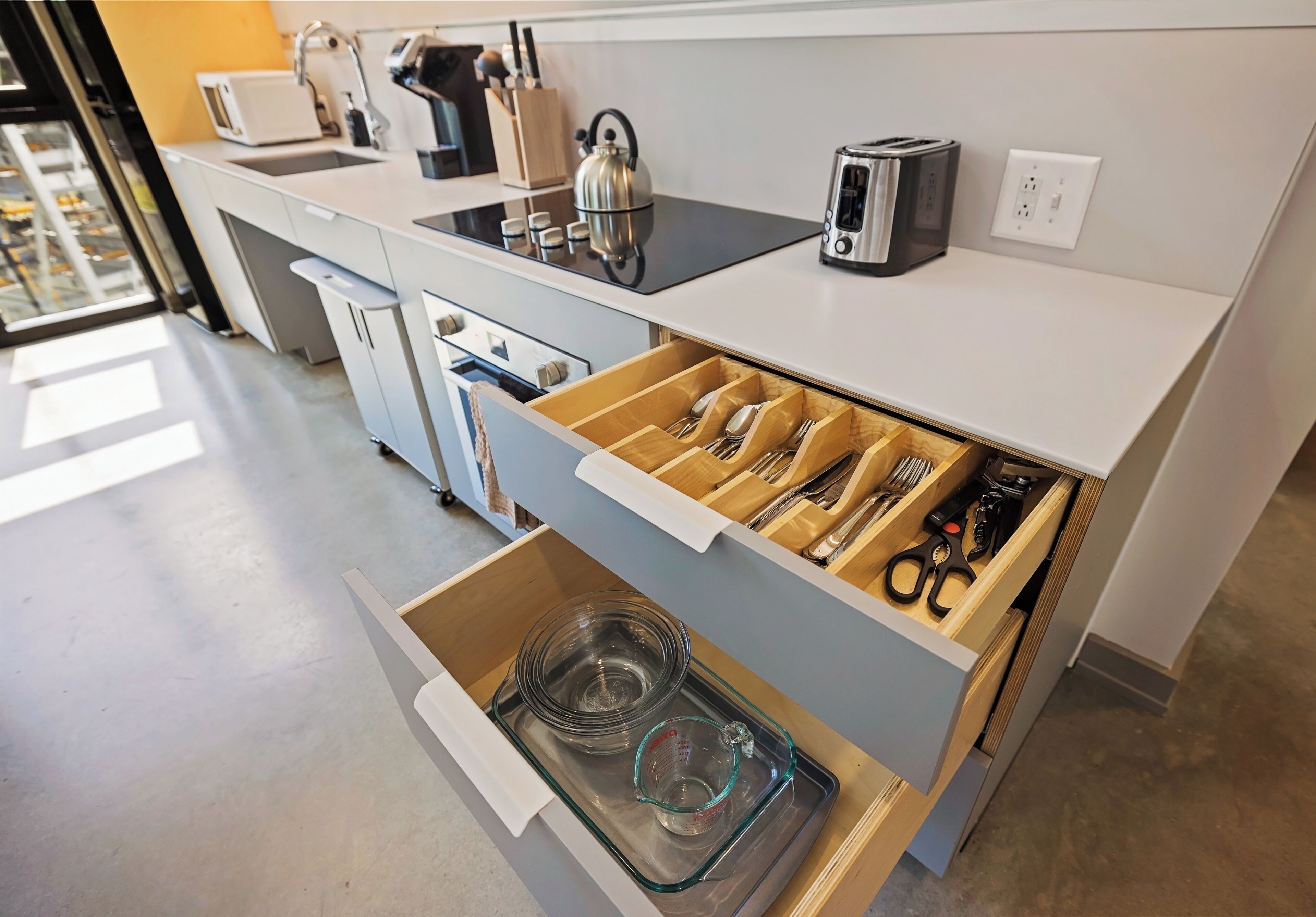 A modern kitchen with a built-in toaster, kettle, and a drawer organizer for utensils.