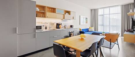 A modern kitchen with grey cabinets, a wooden dining table, and a blue sofa in the living area.