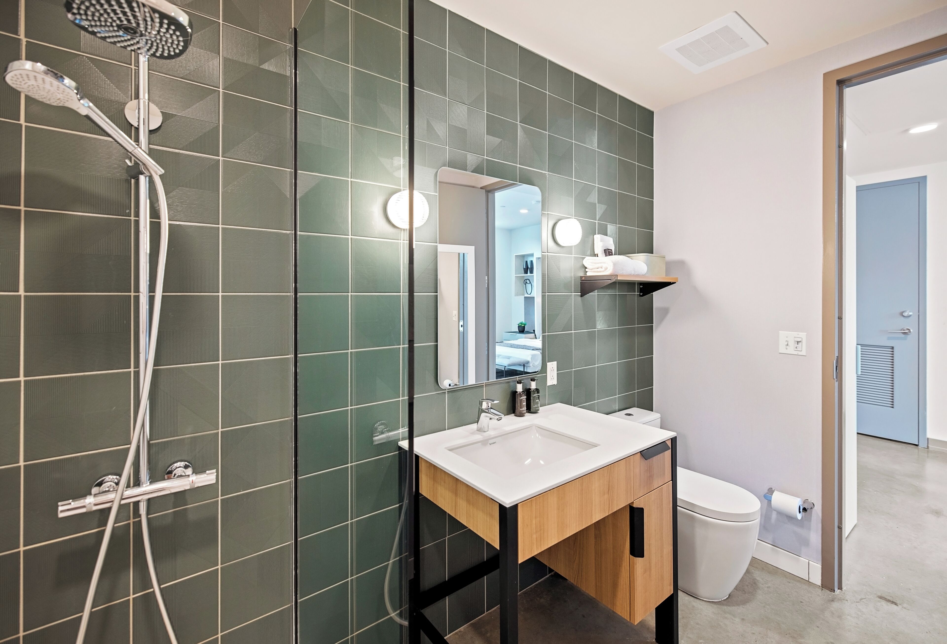 A modern bathroom with a shower, sink, and toilet.