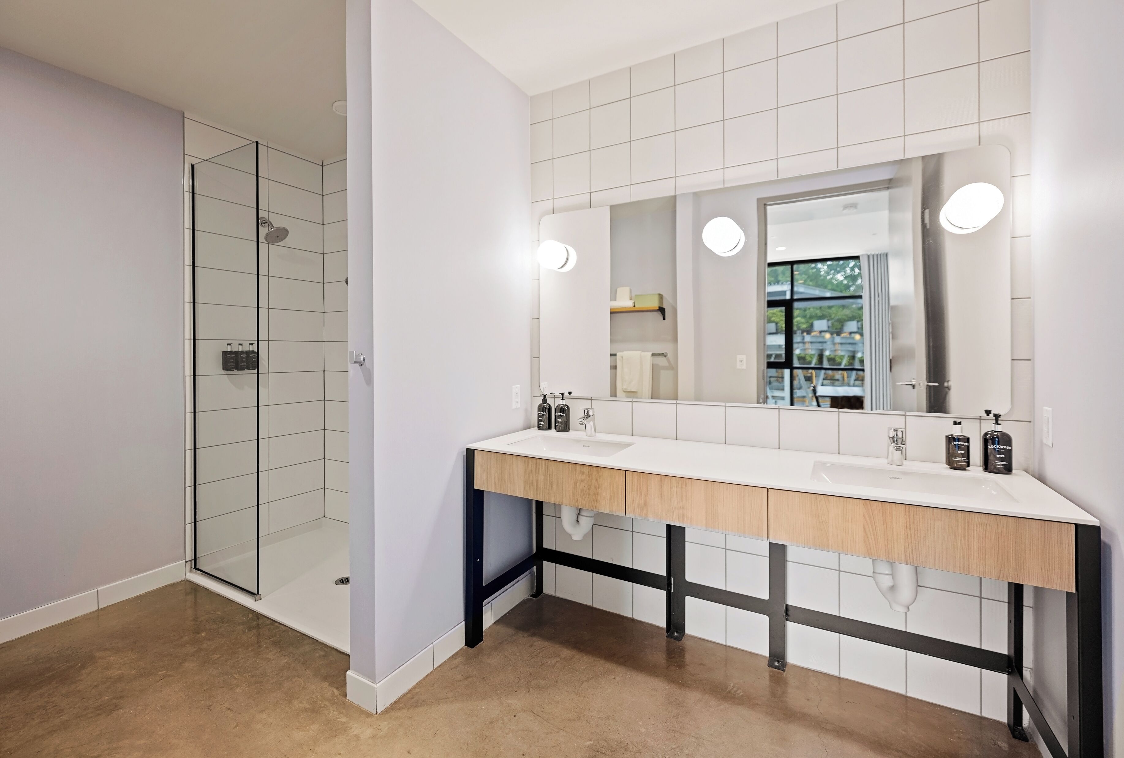 Un baño moderno con cabina de ducha de vidrio, tocador doble y un espejo grande.