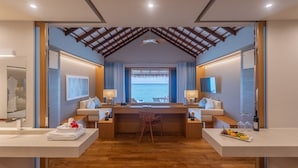 Une chambre moderne équipée d’un bureau, de deux chaises, offrant une vue sur la mer et dotée d’un ventilateur de plafond.