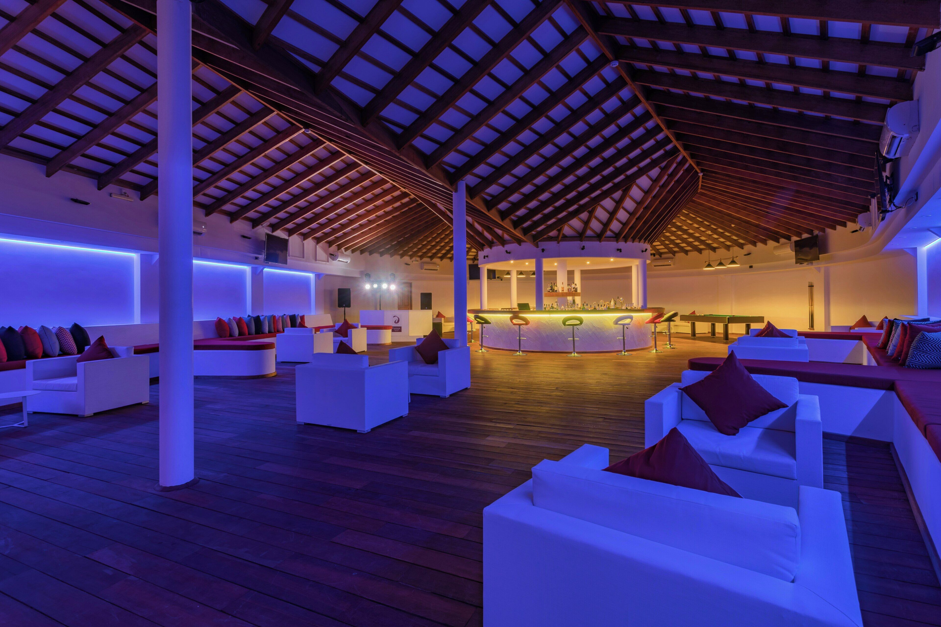 A spacious indoor area with white sofas and a bar area.