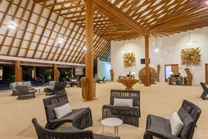 Un'ampia area interna caratterizzata da travi in legno, mobili in vimini e decorazioni murali.