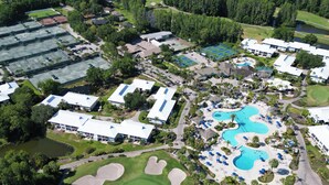 An aerial view of a resort with multiple buildings, a large swimming pool, and golf course. - 5 room TampaGolfVillas by AmericanVacationLiving (Wesley Chapel)