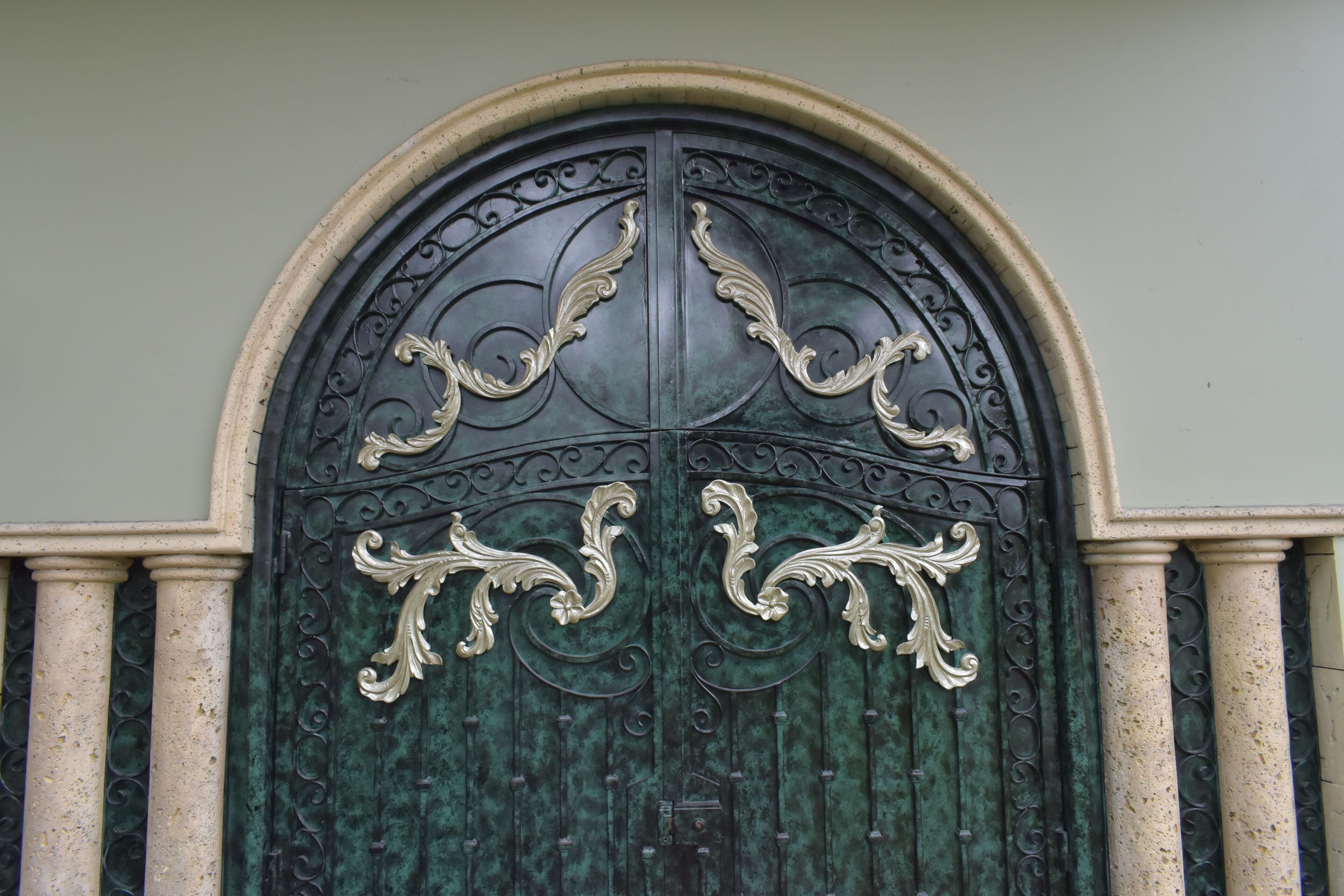 Una puerta metálica grande y ornamentada con diseños intrincados y una cerradura central.