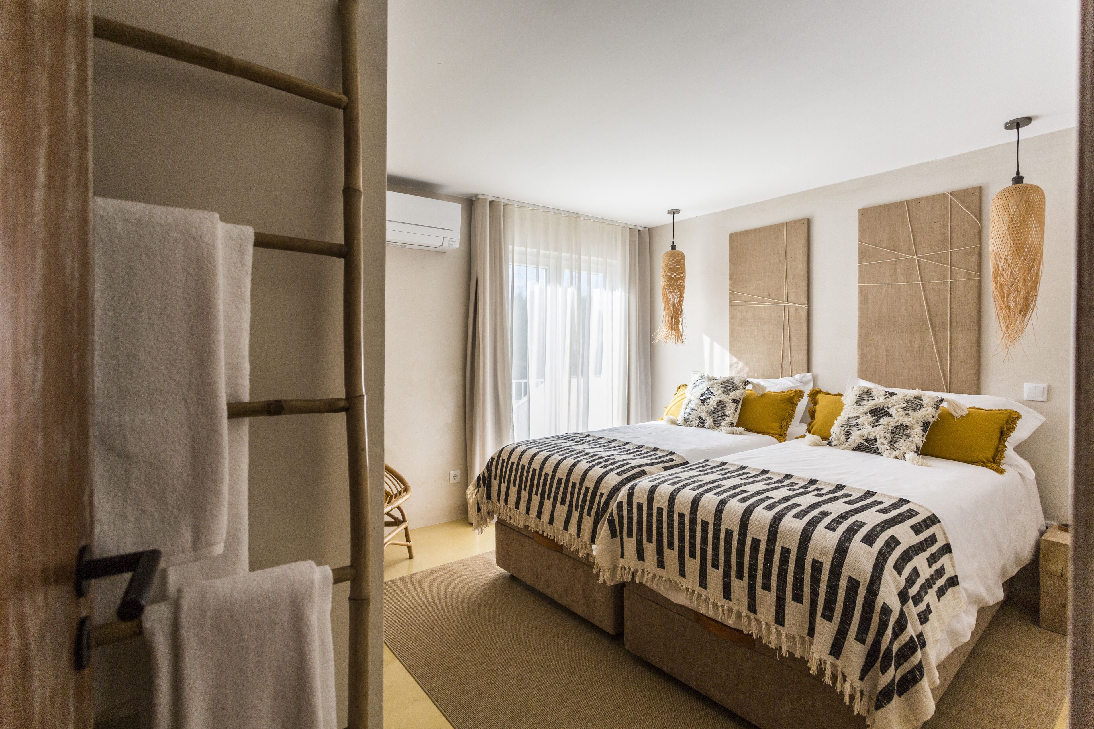 Quarto com uma cama grande, uma escada de madeira e um ar condicionado fixado na parede.