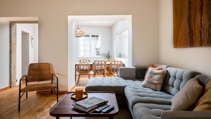 En moderne stue med sofa, sofabord og spiseområde med stole og bord.