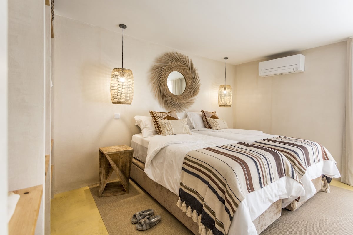 Ein Schlafzimmer mit einem Bett, Nachttischen, einem Spiegel und Pendelleuchten.