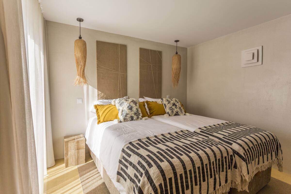 Ein Schlafzimmer mit einem großen Bett, zwei Pendelleuchten und einem kleinen Nachttisch.