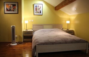 A bedroom with a bed, two bedside tables, two wall-mounted lamps, a standing heater, and two framed pictures on the wall. - Chambres d'Hotes L'Odysée (Dommartemont)