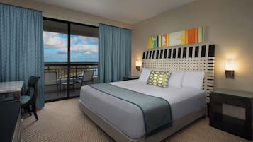 Een hotelkamer met een groot bed, een bureau en een stoel. Er is een balkon met uitzicht.