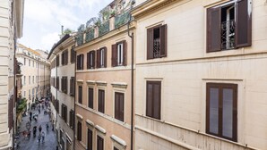 Una calle estrecha flanqueada por edificios de varios pisos con arquitectura tradicional, que incluyen balcones y contraventanas.
