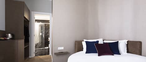 Une chambre d’hôtel moderne dotée d’un grand lit, d’une armoire intégrée et d’un espace douche.