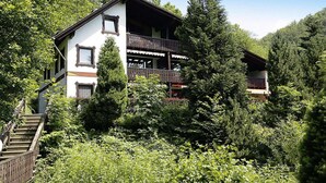 Eine zweistöckige Chalet mit Balkon, umgeben von dichtem Wald.