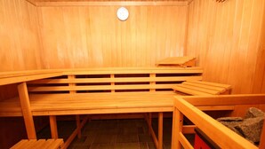 Eine Sauna mit Holzbänken und einem roten Korb.