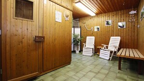 Ein Holzinterieur mit einer Rezeption, zwei weißen Stühlen, einer Bank und einer Topfpflanze.