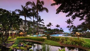 A resort with a pool, palm trees, and a building with multiple floors.