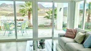 A spacious living area with a glass coffee table, a sofa with cushions, and a dining area with chairs and a table. - Villa Blanca views and pool (Níjar)