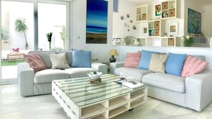 A modern living room with two white sofas, a glass coffee table, and a bookshelf. - Villa Blanca views and pool (Níjar)