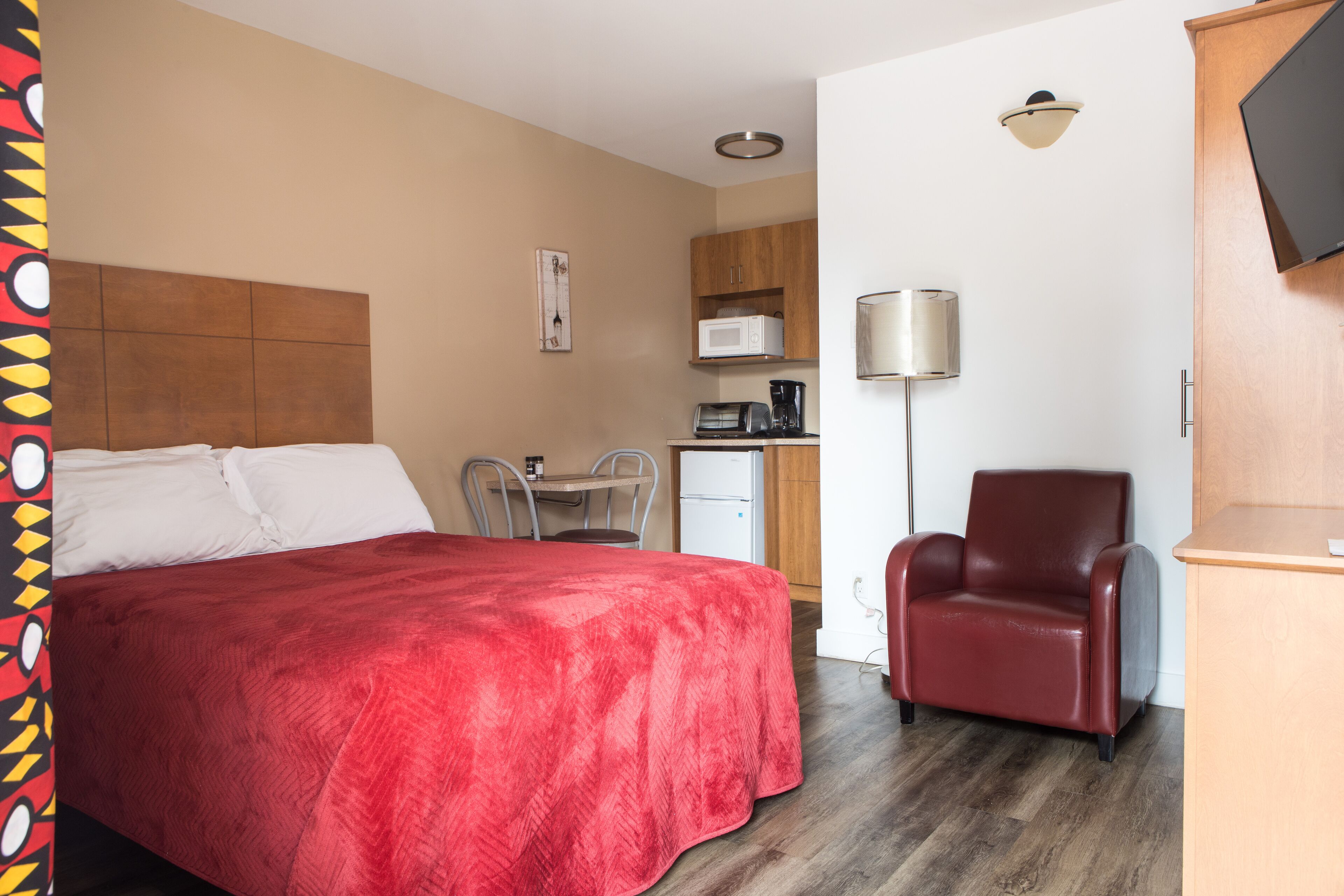 Ein Hotelzimmer mit Bett, Schreibtisch mit Stuhl, einer Mikrowelle, einer Kaffeemaschine und einem Fernseher.