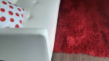 A white sofa with red polka dot pillows and a red shag rug.