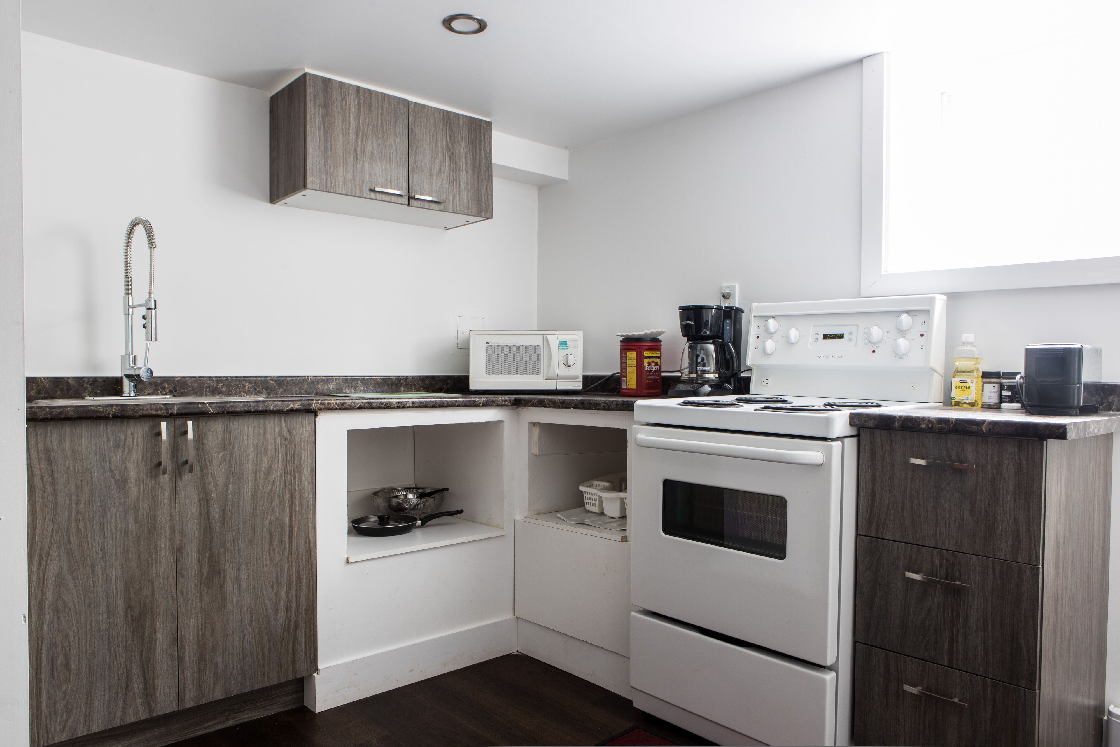 A modern kitchen with white cabinets, a microwave, a coffee maker, and an oven.